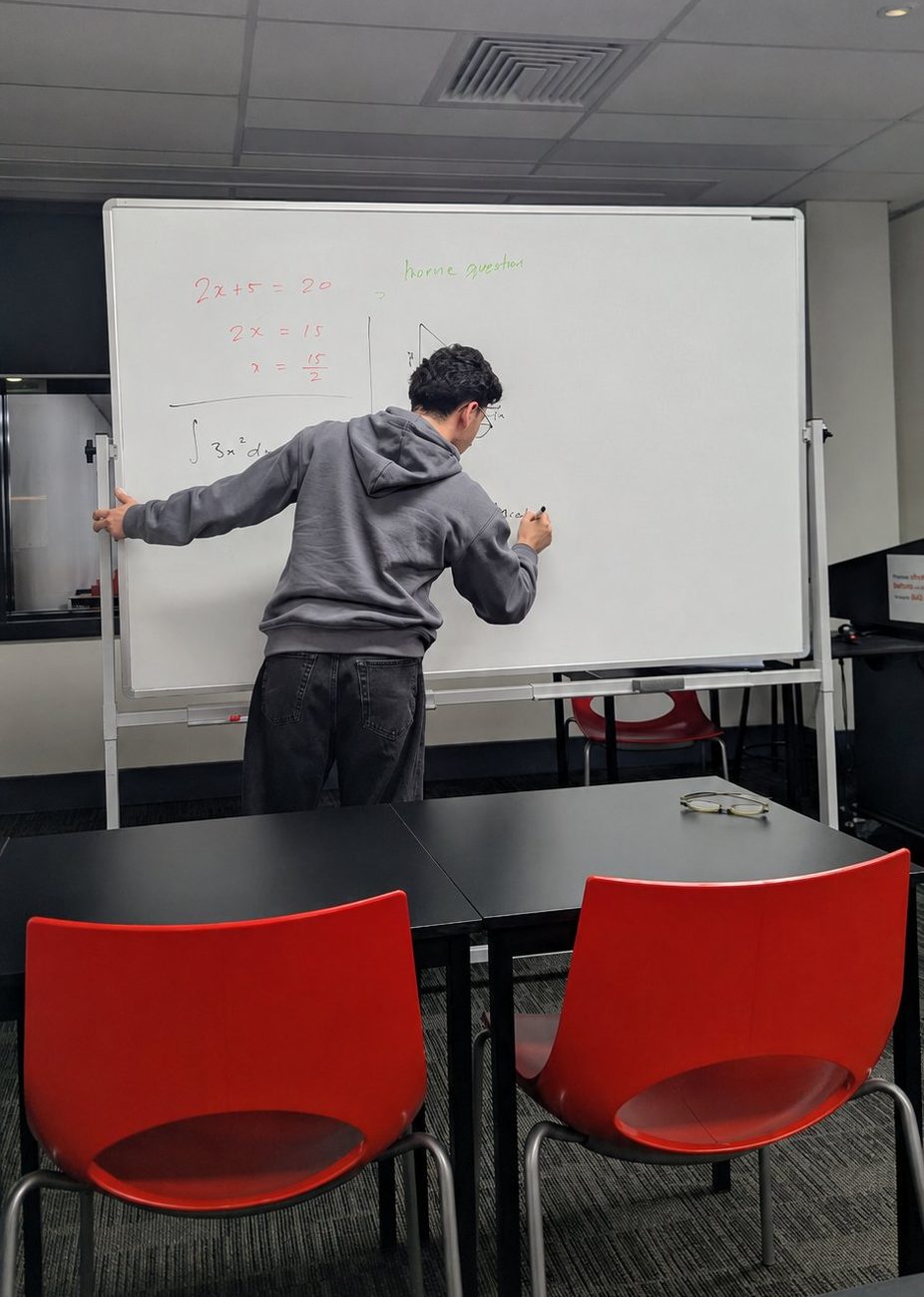A Vertex tutor working through a problem on the whiteboard